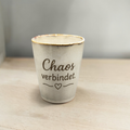 Keramikbecher „Chaos verbindet“ frontal auf hellem Holztisch