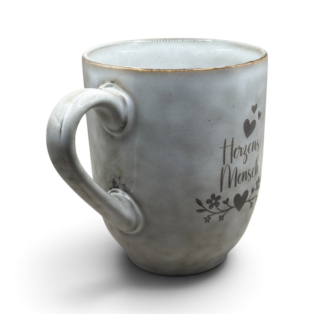 Graue Keramiktasse mit Herzensmensch-Gravur in schräger Ansicht mit Henkel