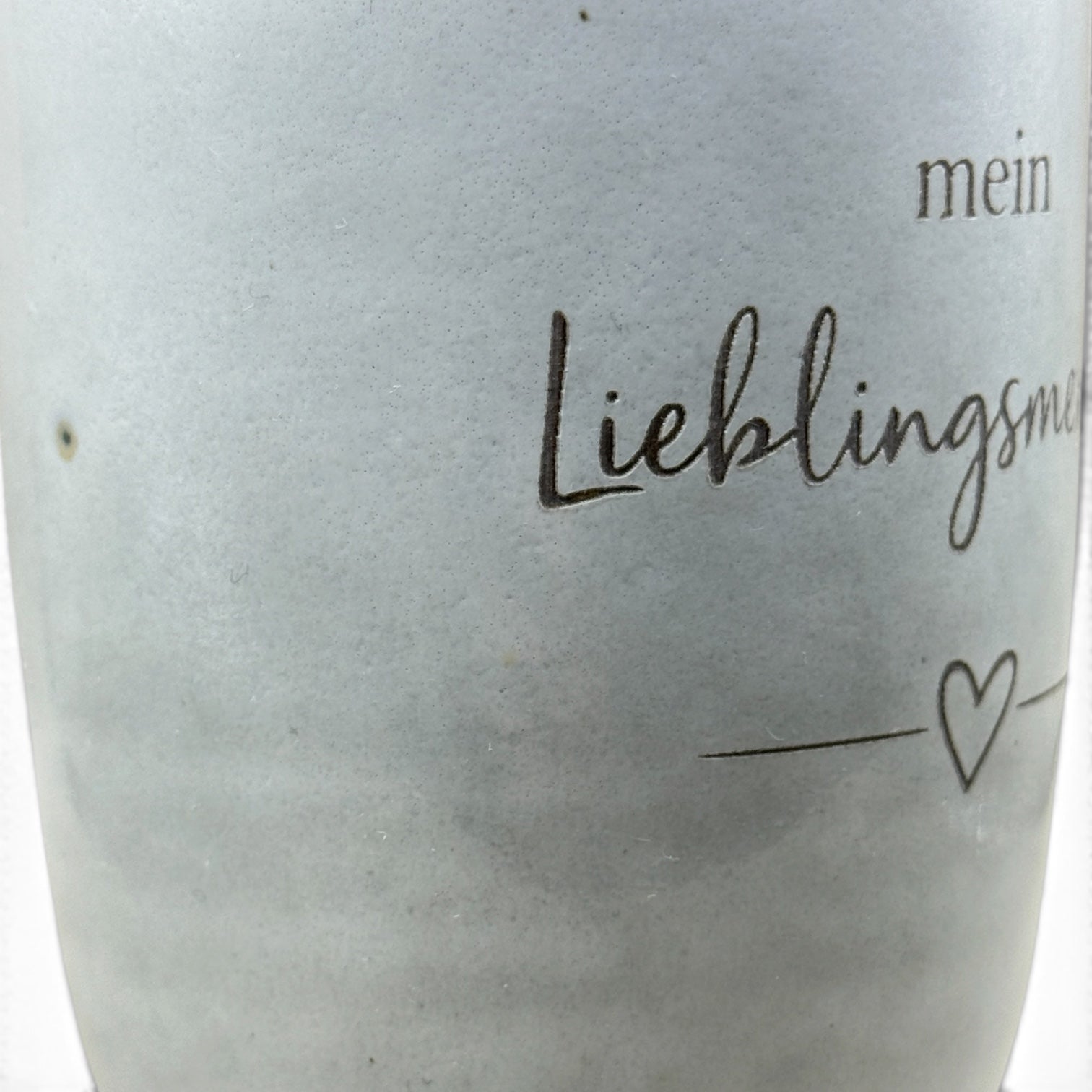 Detail der Lasergravur „Mein Lieblingsmensch“ mit Herzmotiv auf grauer Keramiktasse