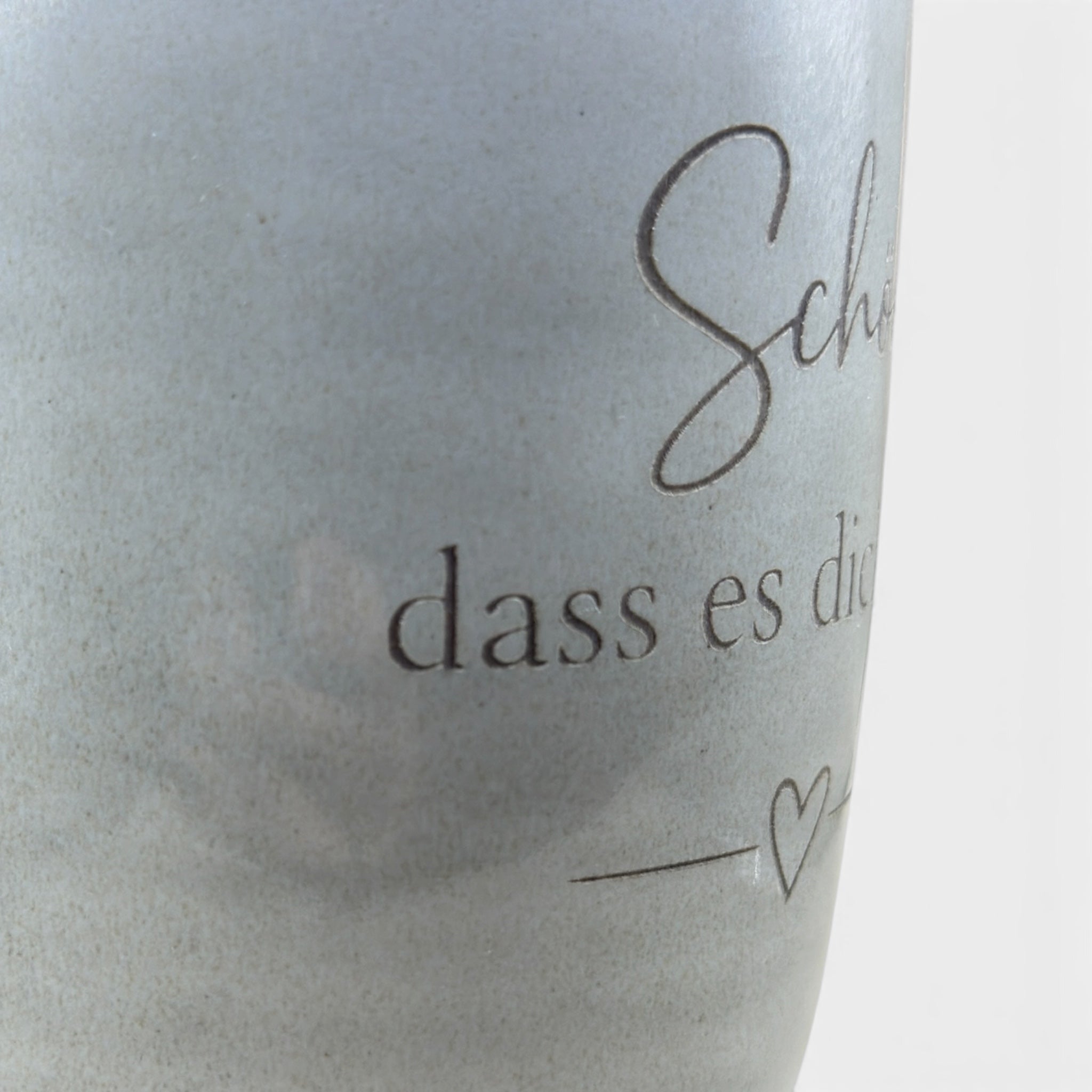 Detail der Lasergravur „Schön, dass es dich gibt“ auf grauer Keramiktasse