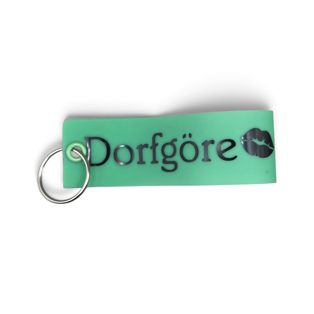 Grüner Vinyl-Schlüsselanhänger mit Aufschrift „Dorfgöre“ und Lippenmotiv