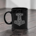 Schwarze Wikinger Tasse aus Keramik mit gravierten Thors Hammer Mjölnir auf Holztisch 