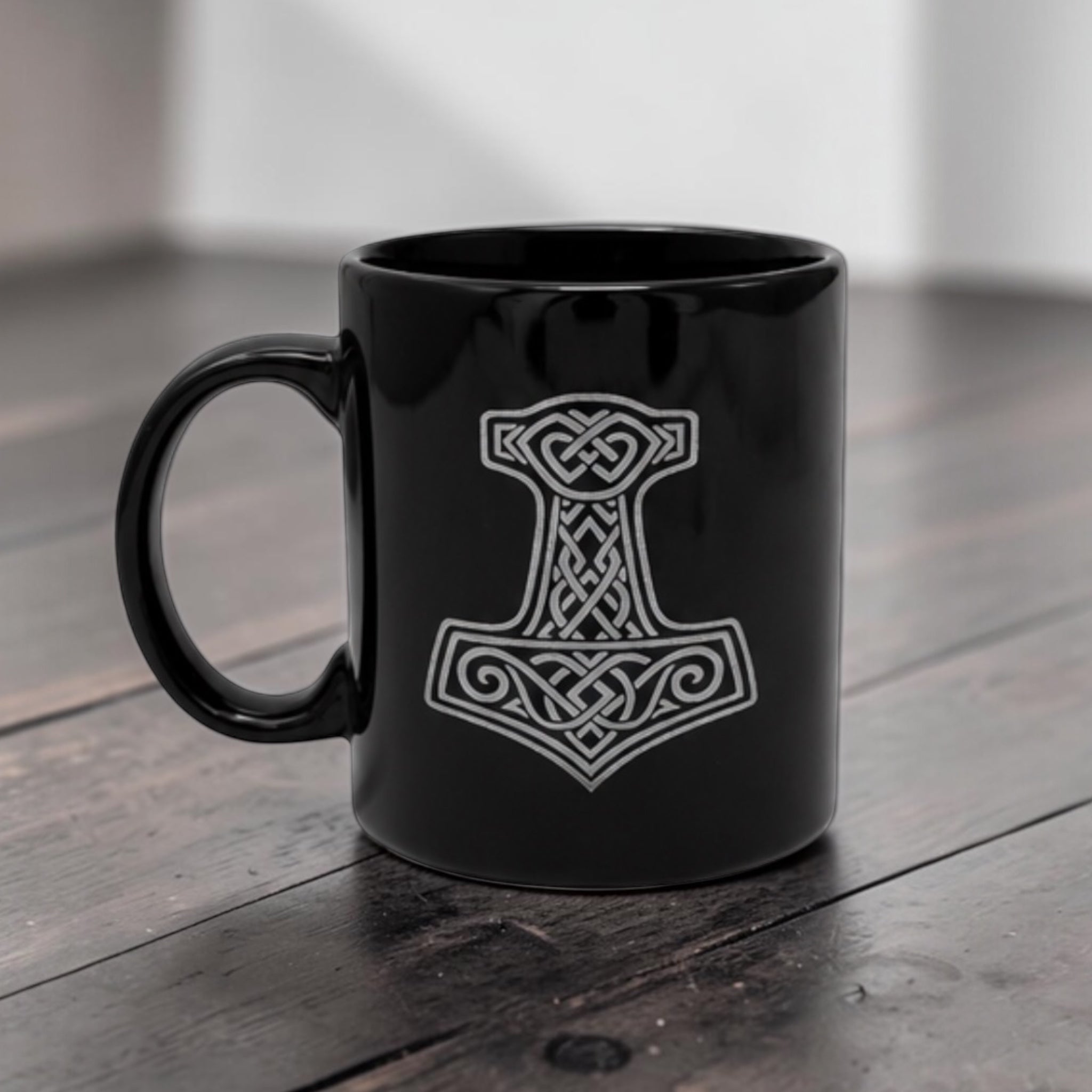Schwarze Wikinger Tasse aus Keramik mit gravierten Thors Hammer Mjölnir auf Holztisch 